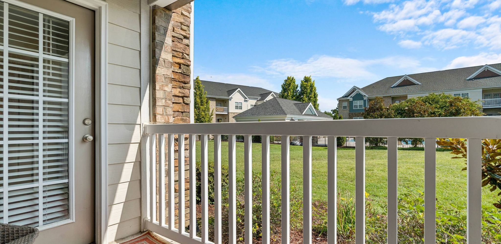 Hawthorne at Horse Pen Creek apartment patio with a view of community exterior, large green lawn and outdoor pool area
